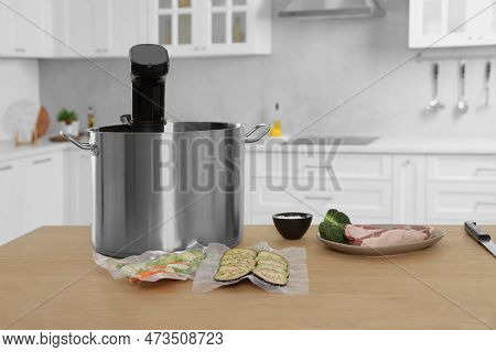 Pot With Sous Vide Cooker, Vacuum Packed Vegetables And Ingredients On Table In Kitchen. Thermal Imm