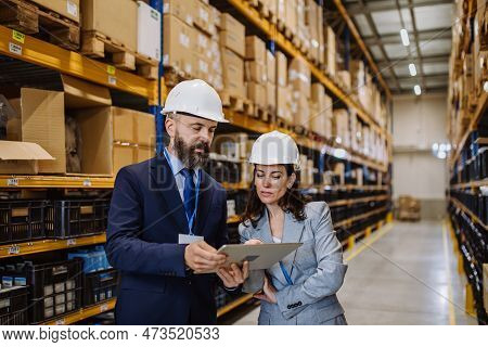 Managers In Suit Controlling Goods In A Waehouse.