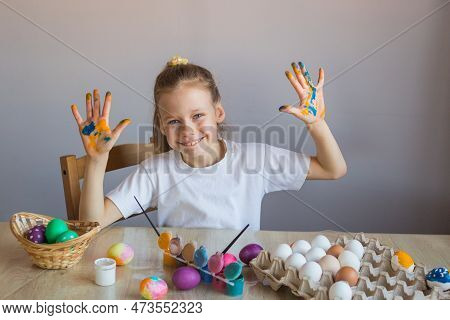 A Smiling Girl In A White T-shirt Shows Her Palms Covered In Paint Stained With Eggs. Easter. Spring