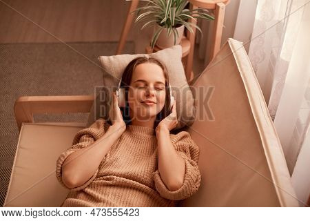 Portrait Of Joyful Relaxed Caucasian Young Woman Listening Music While Resting On Couch At Home, Kee