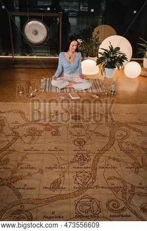 A Young Woman Sits In The Lotus Position Before The Start Of The Game Leela And Holds A Game Cube In