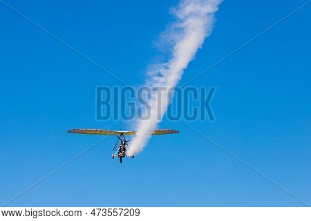 A Paraglider With A Cradle On Wheels Leaves A White Trail In The Blue Sky