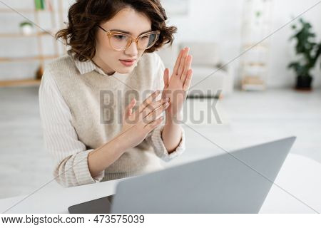 Young Teacher In Glasses Showing Two Handed Sign Language Gesture While Looking At Laptop.