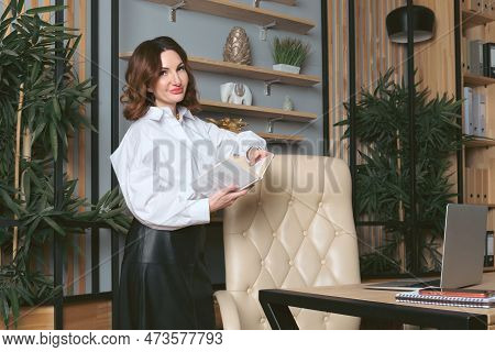 Portrait Of A Business Woman With Shoulder-length Wavy Red Hair In A White Blouse. Business Woman Is
