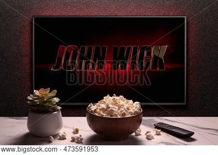 Tv Screen Playing John Wick Chapter 4 Trailer Or Movie. Tv With Remote Control, Popcorn Bowl And Hom