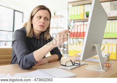 Suspecting Woman With Magnifying Glass Seeks Information On Internet In Office Closeup. Fact Checkin