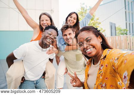 A Lovely Hispanic Girl Taking A Selfie Portrait With Her Multiracial Teenage Friends On Piggybacks W