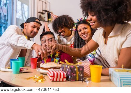 Multi-ethnic Group Of Friends At A Birthday Party On The Sofa At Home With A Cake And Gifts, Smiling