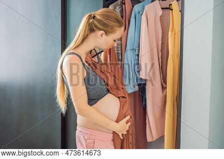 A Pregnant Woman Has Nothing To Wear. A Pregnant Woman Stands In Front Of A Closet With Clothes And 