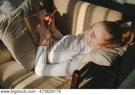 Woman Writing Ideas In Nobook, Doing Beauty Face Mask For Skincare Relaxing In Living Room At Home. 