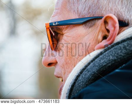 Strasbourg, France - March 29, 2023: Side Vide Of Senior Man Speaking Open Mouth Wearing Ray-ban Sun