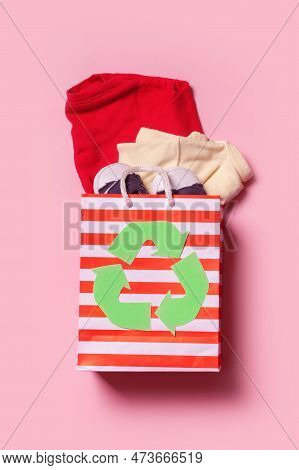 Children's Clothes In Shopping Bag With A Recycling Symbol. Second Hand, Clothing Recycling Concept