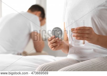 Couple In Bedroom. Woman Taking Emergency Contraception Pill, Closeup