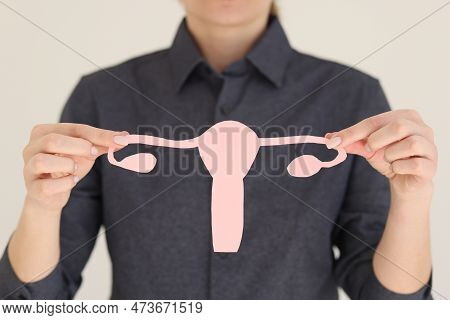 Hands Of Woman Holding Pink Paper In Shape Symbol Of Fight Against Female Infertility On White. Conc