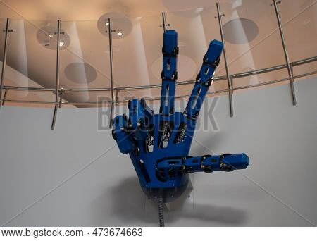 A Large Mechanical Hand At A Robot Exhibition Shows A Sign Of Victory. The Robotic Arm Is Controlled