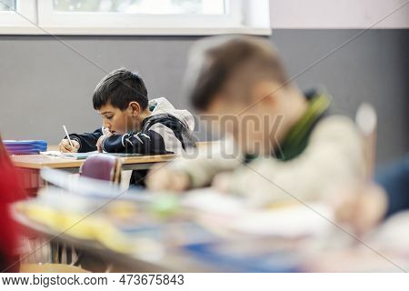 A Clever Indian Boy Writes Downright Answers In Notebook At Classroom.