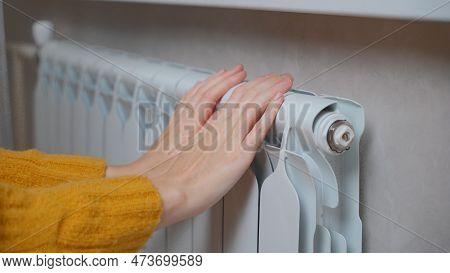 Female Hands Are Trying To Keep Warm On An Aluminum Radiator. A Woman Warms Herself Near A Radiator 