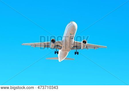 Plane Soaring Overhead, With A Clear View Of The Underbelly And Wings Against A Clear Blue Sky.