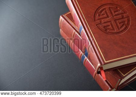 Stack Of Books With Brown Leather Cover With Engraved Symbol Of Shenist Culture And Religion On Blac