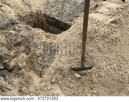 A Hole Dug In The Ground With A Shovel Nearby. Place In The Sand At The Cemetery. Burial Grave Dug W