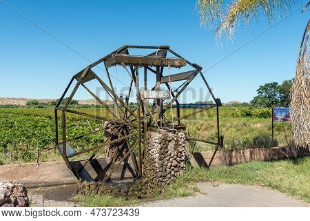 Keimoes, South Africa - Feb 25, 2023: An Irrigation Canal, Working Waterwheel Replica And Vineyard, 