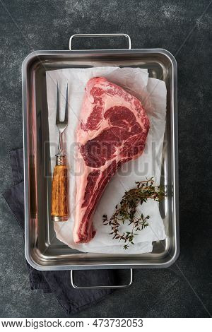 Fresh Tomahawk Raw Steak. Dry Aged Raw Tomahawk Beef Steak With Herbs And Salt On Old Wooden Backgro