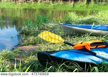 Tourist Canoes With Paddles Stand On The River Coast In Summer On A Water Hike. Rafting On Inflatabl