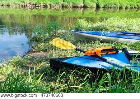 Tourist Canoes With Paddles Stand On The River Coast In Summer On A Water Hike. Rafting On Inflatabl