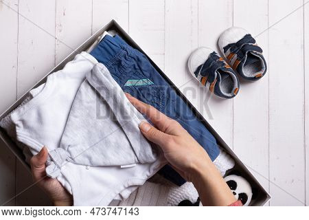 Female Hands Put Childrens Clothes, Shoes And Toys Into A Box. Second Hand, Clothing Recycling Conce