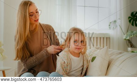 Caucasian Mother Comb Hair Of Cute Preteen Child Girl Daughter Mom Babysitter Help Little Child Kid 