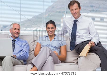 坐在沙发上微笑相机在 staffroom 的商务人士