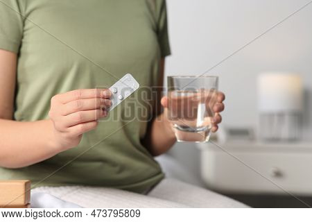Woman Taking Emergency Contraception Pill In Bedroom, Focus On Hand