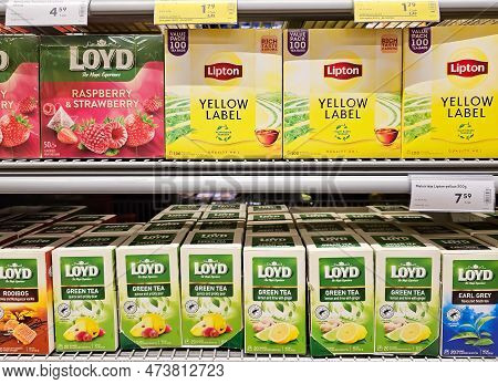Latvia, Riga, April, 2023: Row Of Yellow Color Packs Of Lipton Tea An Loyd Green Tea On The Supermar