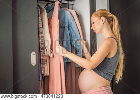 A Pregnant Woman Has Nothing To Wear. A Pregnant Woman Stands In Front Of A Closet With Clothes And 