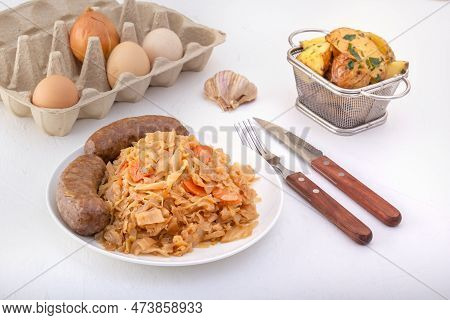 Braised Cabbage - Bigos And Grilled Sausage In A White Porcelain Plate Against The Background Of Chi