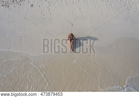 Young Woman In A Bikini Lying On The Back On The Sand Near The Waves Of Indian Ocean. Top View. Cros
