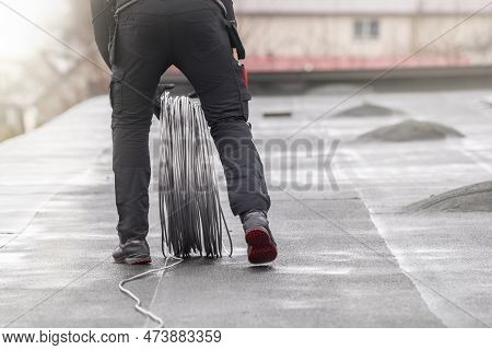 Ground Wire. A Worker Lays A Ground Cable On The Roof Of A Building. Electrician Fixing Aluminum Wir