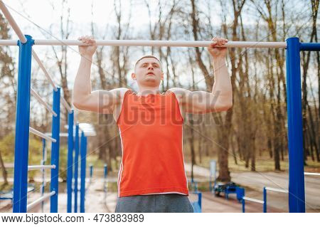 Graceful Gymnast Doing Pull-ups On High Bar For Athletic Training. A Male Gymnast Is Practicing His 