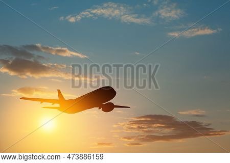 Airplane Taking Off At The Sunset Sky. Silhouette Of Aircraft In The Sky.