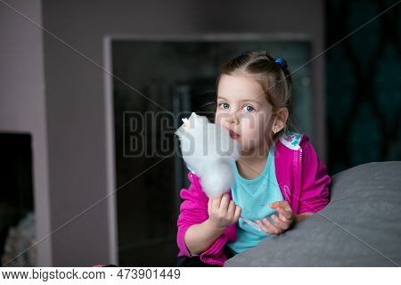 Curious, Cute Fair Haired Little Girl Joying, Eating Cotton Candy, Candyfloss On Stick And Looking A