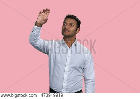 Brown Indian Businessman Touching Imaginery Virtual Screen. Isolated On Pink Background.
