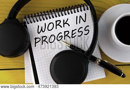Work In Progress - Words On A White Notepad On A Yellow Background With Headphones, A Cup Of Coffee 
