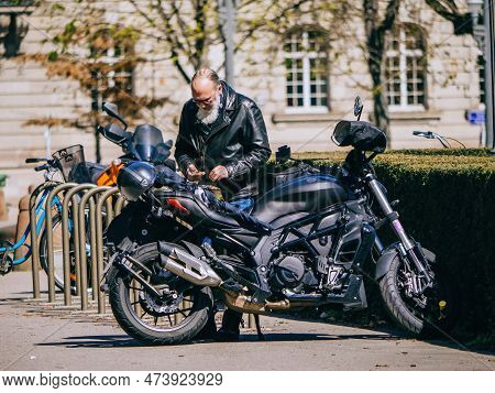 Strasborg, France - Mar 29, 2023: A Senior Man Wearing A Leather Jacket And Sports Helmet Parks His 