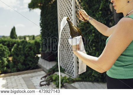 Young Woman Opens A Bottle Of Sparkling Wine By The Knife. Sabrage. Close Up.