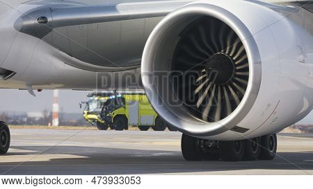 Fire Truck Of Airport Rescue And Fire Brigade Behind Engine Of Airplane On Runway. Themes Emergency 