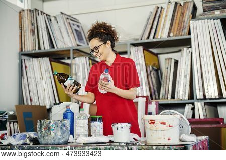 A Worker Reading Instructions On Bottles Of Paint Thinner In Printing Shop.