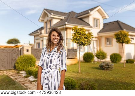 Beautiful Young Woman Standing In Front Of Her New House Happy After Purchasing New Property