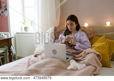 Sick Teenage Girl Laying In Her Bed With Laptop.