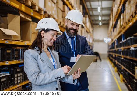 Managers In Suit Controlling Goods In A Waehouse.
