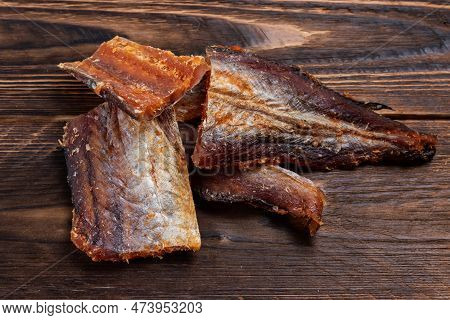 Pieces Of Cleaned Dried Fish On Wooden Background. Dry Peppered Pollack. Amber With Pepper.